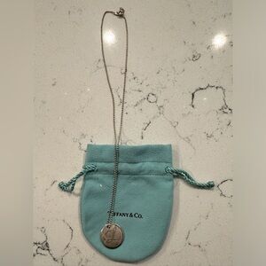 Sterling silver Tiffany “L” monogrammed disc necklace.